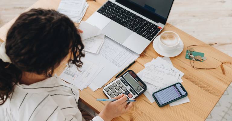 Bovenaanzicht van een vrouw die thuis in de keuken werkt met financiƫle papieren